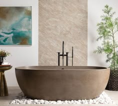 a bath tub sitting on top of a white floor next to a painting and potted plant