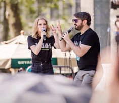 a man and woman standing next to each other while holding microphones in their hands