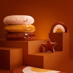 four pillows stacked on top of each other in front of an orange wall with a star