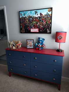 there is a blue dresser with many pictures on it and a red lamp next to it