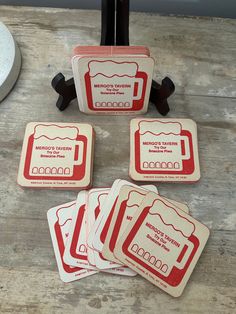 four red and white coasters sitting on top of a wooden table next to a clock