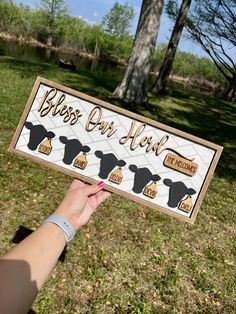 a person holding up a sign that says,'bless our herd'in front of some trees