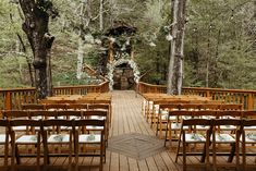 rows of wooden chairs set up for an outdoor wedding ceremony in the middle of a forest