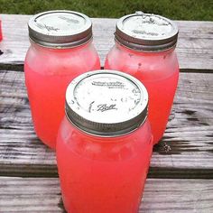 three red mason jars sitting on top of a wooden table