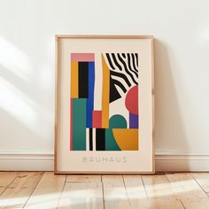 a framed art print with the word bauhus on it in front of a white wall