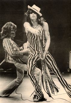 an old photo of a man in striped clothes holding a guitar and wearing a cowboy hat