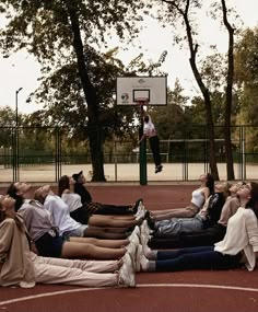 several people laying on the ground in front of a basketball hoop