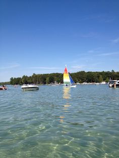 several boats floating in the water near each other on a sunny day with blue sky