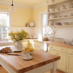 a bowl of lemons on a kitchen counter with plates and bowls in the background