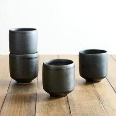 three black cups sitting on top of a wooden table