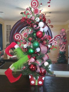 a christmas tree decorated with candy canes, ornaments and elf's feet on a table