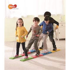 three children are standing on skis in the living room and one child is holding poles