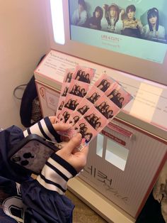 a person holding up some stickers in front of a tv