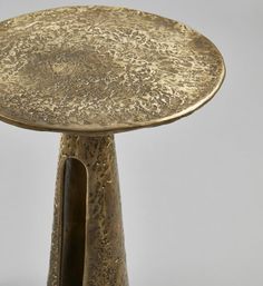 a gold colored table with two legs and a round metal plate on it's top