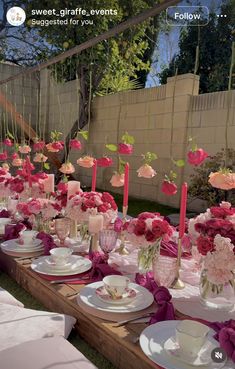 a long table set up with pink flowers and candles for a formal dinner or party