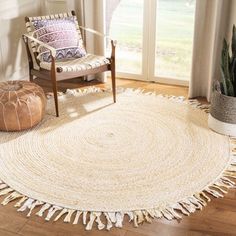 a round rug with tassels on it in a room next to a chair