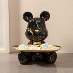 a black and gold bear figurine sitting on top of a plate with candy