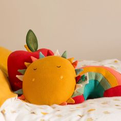 a stuffed animal laying on top of a bed next to a banana and apple pillow