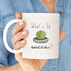 a woman holding a coffee mug with a cactus on it that says, what's up succ?