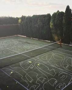 an aerial view of a tennis court with chalk drawings on the ground and trees in the background