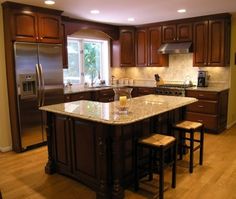 a large kitchen with an island in the middle and two stools next to it