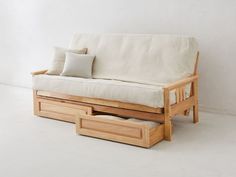 a wooden futon with two drawers underneath it and a pillow on the bottom shelf