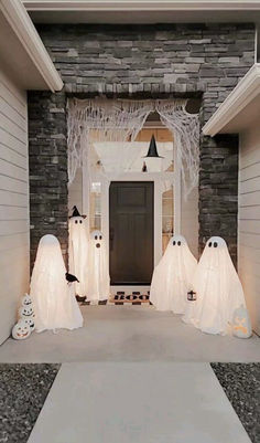 some white ghost decorations in front of a black and white door with lights on it