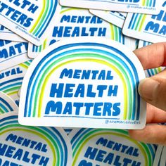 a person holding up a sticker that says mental health matters in blue and green