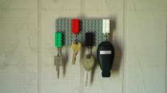 several keys hang on a wall with legos attached to the pegs in front of them