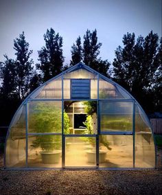 a small greenhouse in the middle of a field at night with lights shining on it