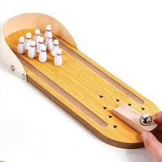 a person is holding a wooden toy bowling set with six pins in the back and four on the front