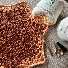 yarn and scissors are sitting on the floor next to a crochet doily