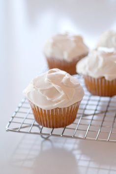 cupcakes with white frosting sitting on a cooling rack