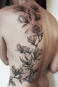 the back of a woman's body with flowers tattooed on her upper and lower half