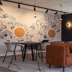 an office with chairs and tables in front of a wall painted with doodles