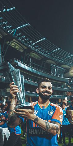 a man holding up a trophy in front of a crowd at a soccer game on a field