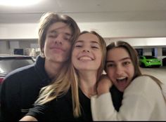 three people posing for a photo in a parking garage with their arms around each other