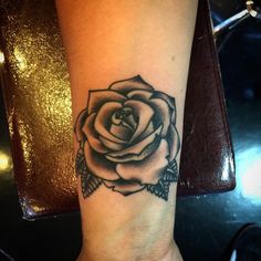 a black and white rose tattoo on the wrist, with an arrow in the center