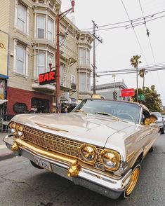 an old car is parked on the side of the road in front of a bar