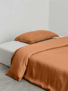 a bed with two pillows and an orange comforter