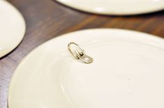 two white plates with rings on them sitting next to each other, one is empty