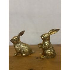 two brass rabbits sitting on top of a wooden table