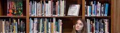 a woman sitting in front of a book shelf filled with books