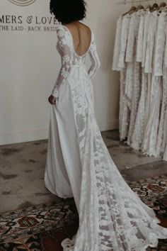 the back of a woman's wedding dress in front of a rack of dresses