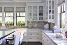 a kitchen with white cabinets and marble counter tops