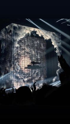 the stage is lit up with clouds and lights as people are clapping in front of it