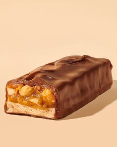 a chocolate bar with nuts and caramel on top, sitting on a beige background