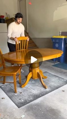 a man standing next to a wooden table with chairs around it and a rug on the floor