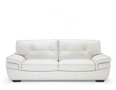 a white leather couch sitting on top of a white floor next to a wooden table