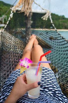 a person laying in a hammock with a drink and a flower on it